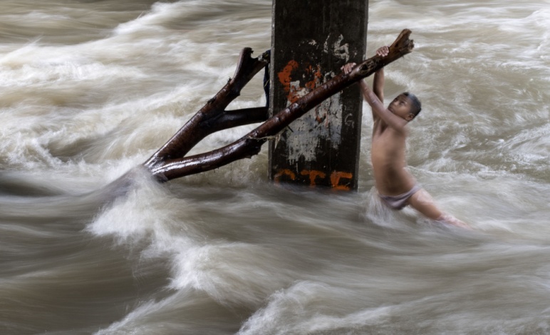 当地时间2018年6月11日,菲律宾马尼拉,儿童在暴雨后桥下暴涨的河水中玩耍(供图 视觉中国).jpg