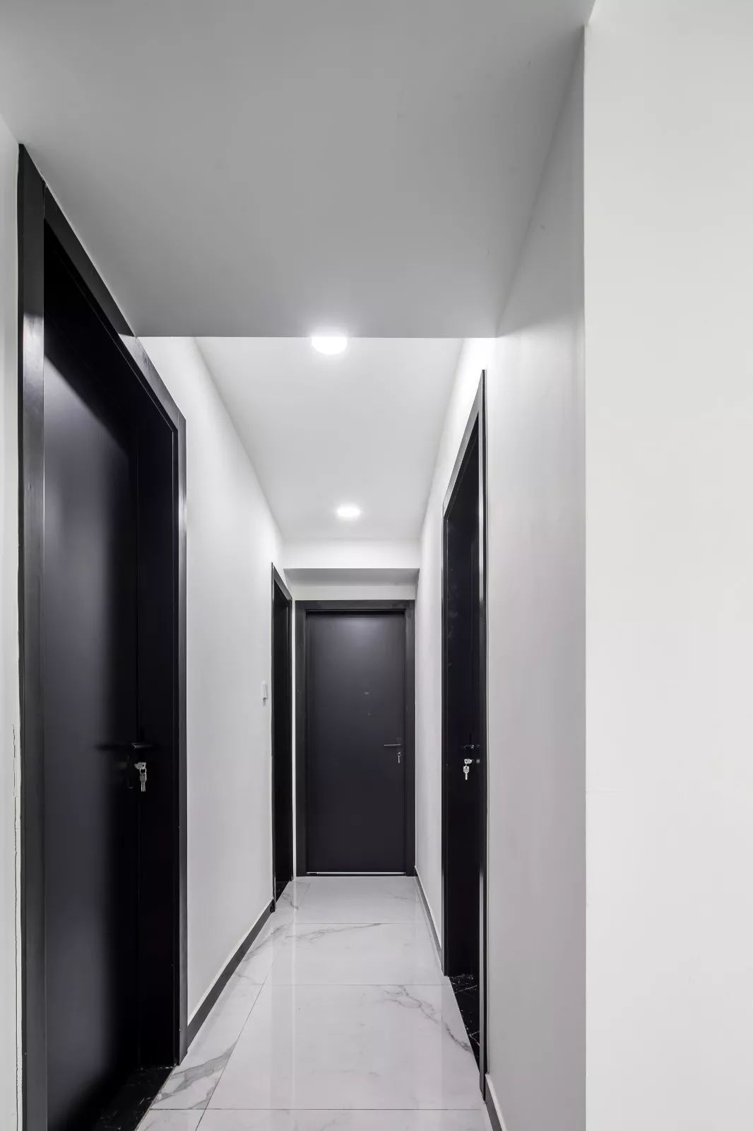 走廊雅致的白色大理石地砖,纯净的墙面,搭配黑色房间门,简洁又时尚.